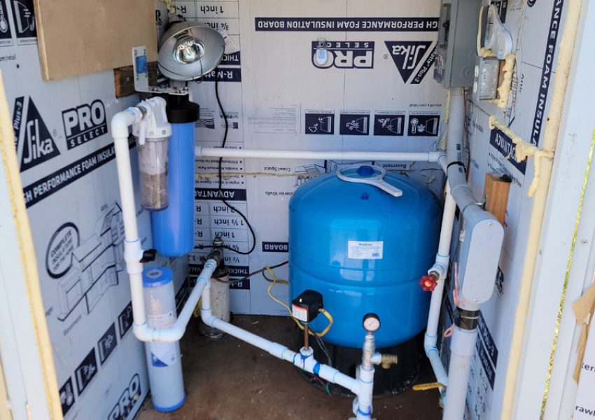 Residential water filtration and pressure tank system with PVC plumbing installed in an insulated well house